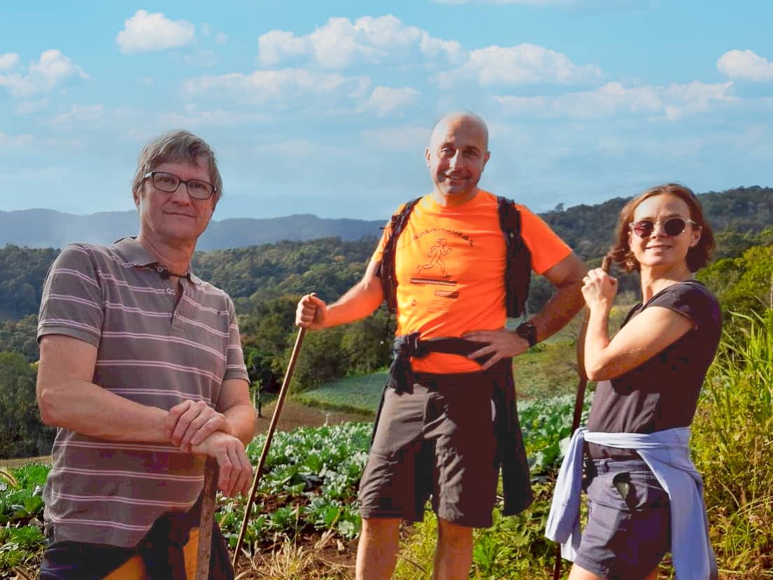 Small group trekking on a scenic mountain trail with lush green valley in the background